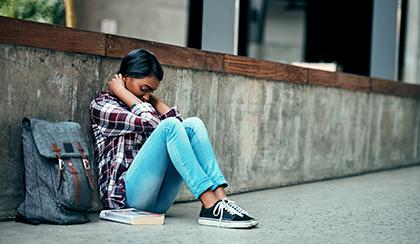 sad student sitting alone on sidewalk