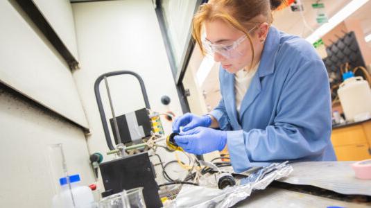 student wearing blue works in lab