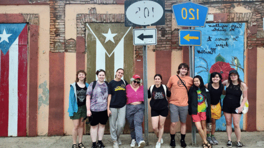 Group of Clark students posing in front of mural on wall in Puerto Rico