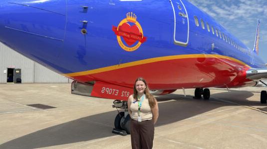 woman standing in front of blue airplane