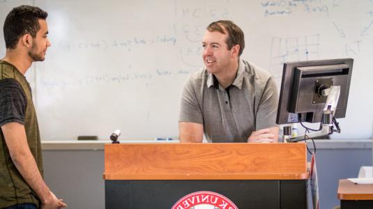 man at computer talking to student